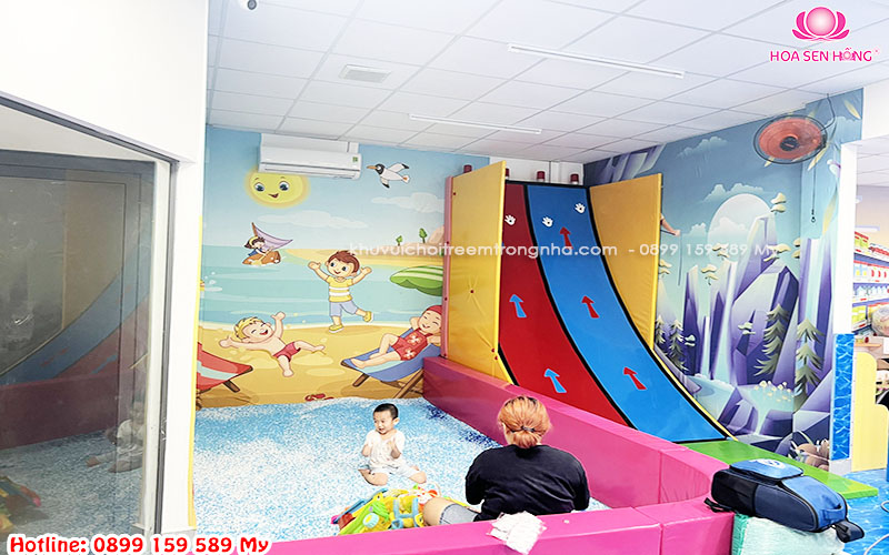 Hình ảnh trẻ em hào hứng leo dốc bấm chuông trong khu vui chơi, với bề mặt leo đầy màu sắc và chuông chiến thắng ở đỉnh cao